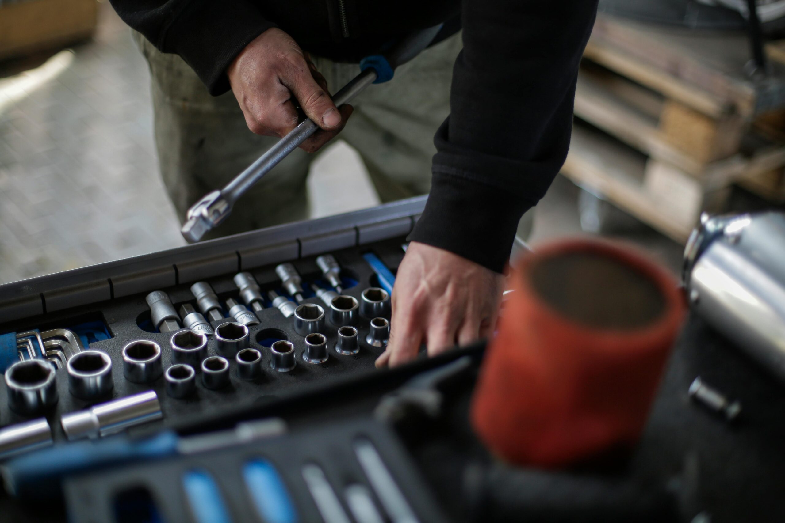 Mechanic's hands selecting socket wrench from toolkit in workshop setting.