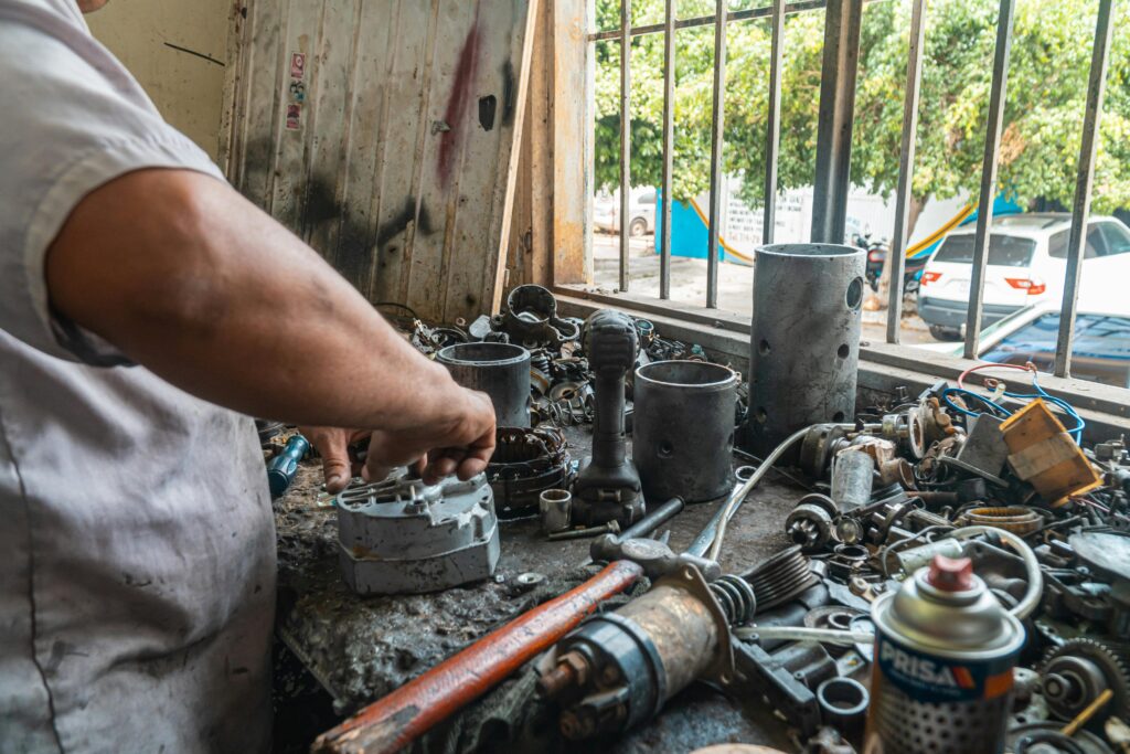 pexels-photo-4116233-4116233 Mechanic organizing auto parts in a busy workshop, surrounded by tools and equipment.