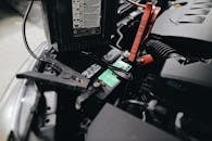 Detailed view of a car battery being jump-started with cables in an engine bay.